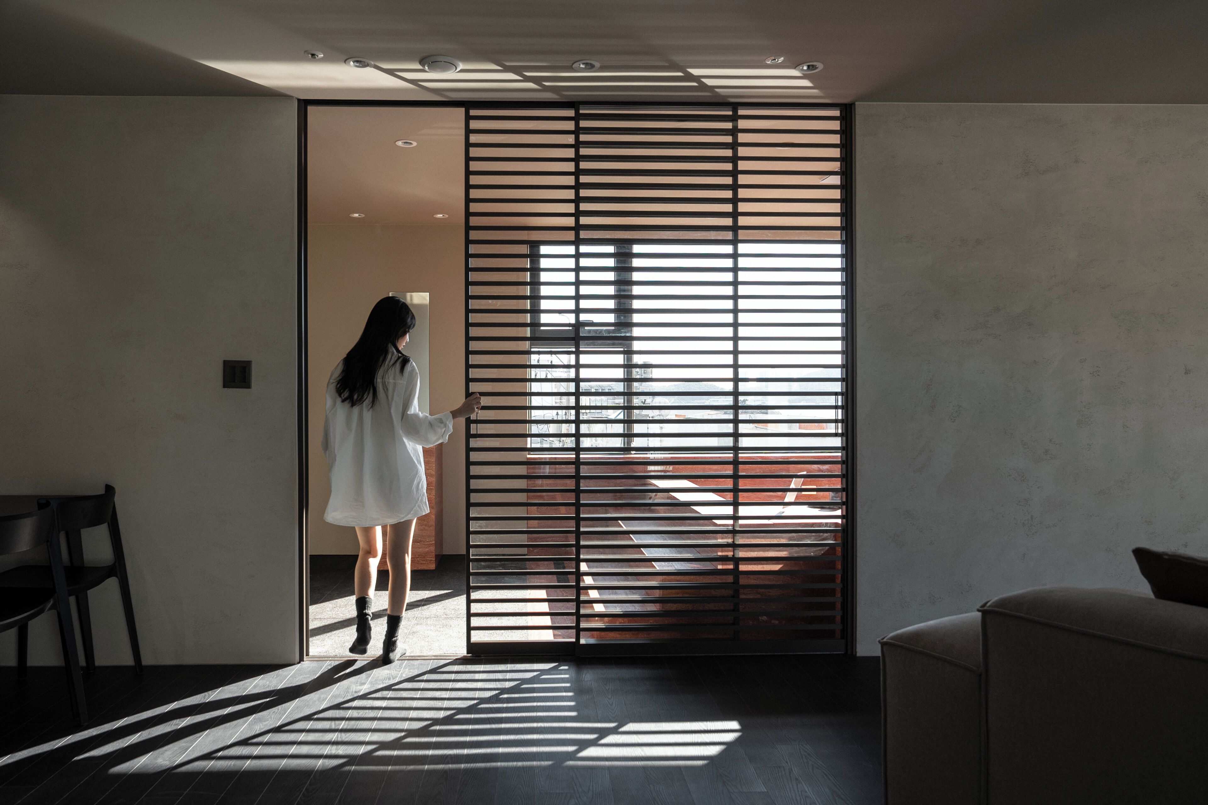 Un interior moderno con una puerta corredera, un sofá y una silla.