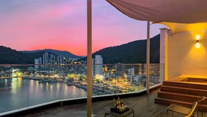 Un balcon offrant une vue sur la ville au crépuscule, un escalier en bois et un espace détente avec une table.