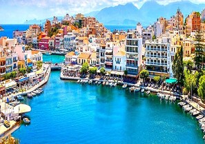 Un paysage urbain côtier avec un port de plaisance, des bâtiments et une mer bleue et limpide.