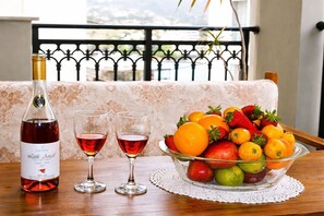 Une bouteille de vin, deux verres et un saladier de fruits sur une table.
