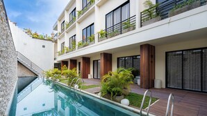 A modern hotel with a swimming pool, wooden deck, and balconies with plants. - Ubud Center Oasis by Betterplace (Ubud)