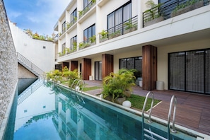 A modern hotel with a swimming pool, wooden deck, and balconies with plants. - Ubud Center Oasis by Betterplace (Ubud)