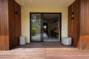 A modern interior with a wooden exterior, a glass door leading to a room with a bed, a desk, and a chair.