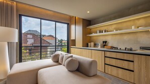 A modern kitchen with wooden cabinets, a built-in oven, and a large window with a view of buildings. - Ubud Center Oasis by Betterplace (Ubud)