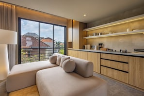 Une cuisine moderne avec des meubles en bois, un four encastré et une grande fenêtre donnant sur les bâtiments environnants.