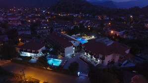 A residential area with houses, a swimming pool, and a mountain backdrop. - HOTEL BİNLİK (Dalyan)