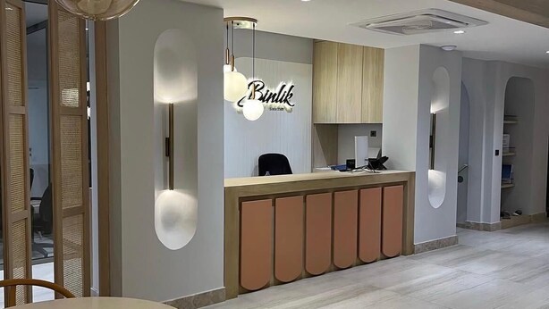 A modern interior with a reception desk, wooden cabinets, and a dining area with a table and chairs. - HOTEL BİNLİK (Dalyan)