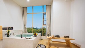 Ein modernes Badezimmer mit Badewanne, Waschtisch und einem Fenster mit Blick auf die Stadt.