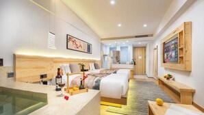 Ein modernes Hotelzimmer mit einem großen Bett, einem kleinen Schreibtisch, einer Badewanne und einem an der Wand befestigten Fernseher.