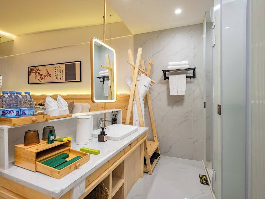 A modern bathroom with a wooden vanity, a large mirror, a shower, and a towel rack.