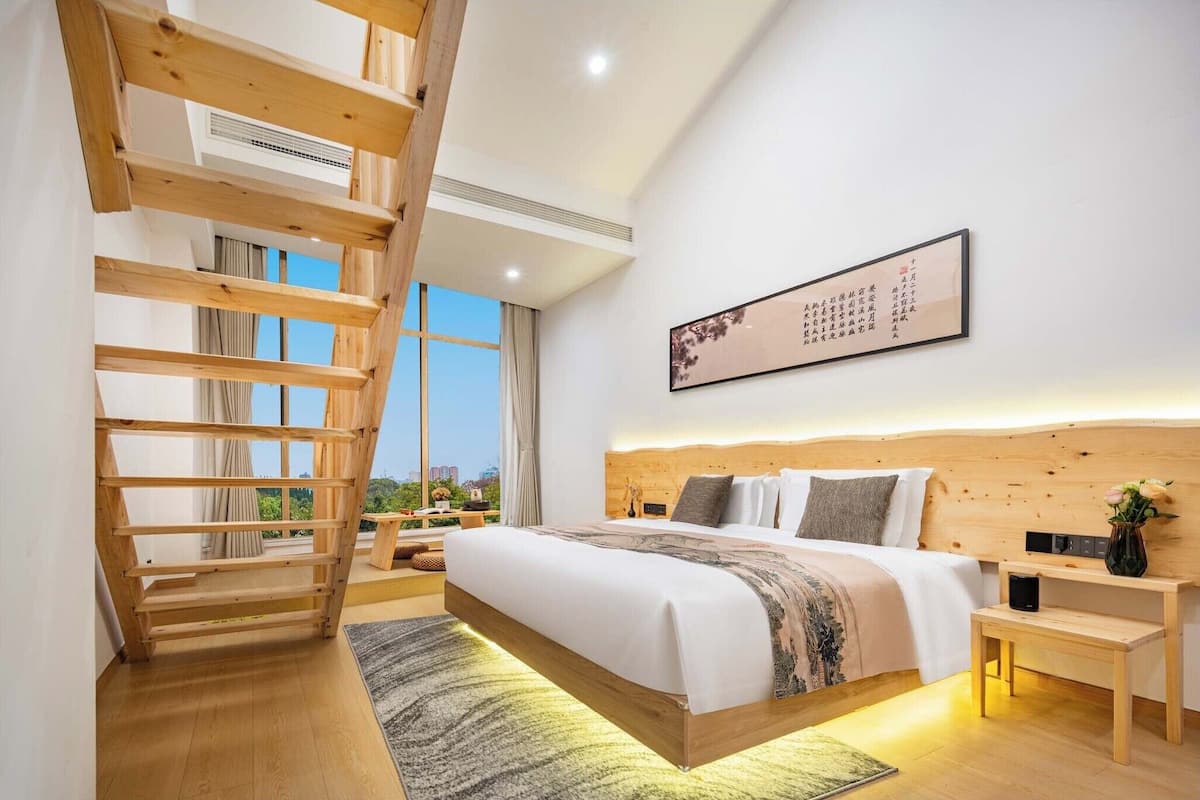 Un dormitorio moderno con una cama de madera, una mesita de noche, una obra de arte colgada en la pared y una escalera.