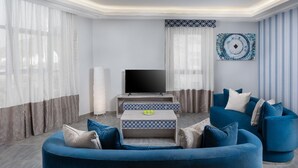 A modern living room with a blue sofa, a flat-screen TV, and a patterned coffee table. - Balensia Hotel (Madinah)