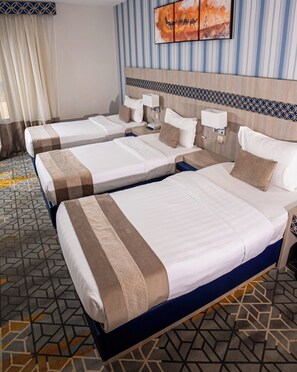 Habitación de hotel con dos camas, piso estampado, televisor montado en la pared y cabecero decorado.