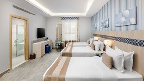 A hotel room with two beds, a TV, a desk, and a bathroom. - Balensia Hotel (Madinah)
