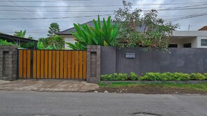 Un'area residenziale recintata con un muro in cemento, un cancello in legno e un cartello che indica 'Angelique Villa'.