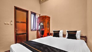 Ein Hotelzimmer mit Bett, Holzschrank, Tür und Klimaanlage.
