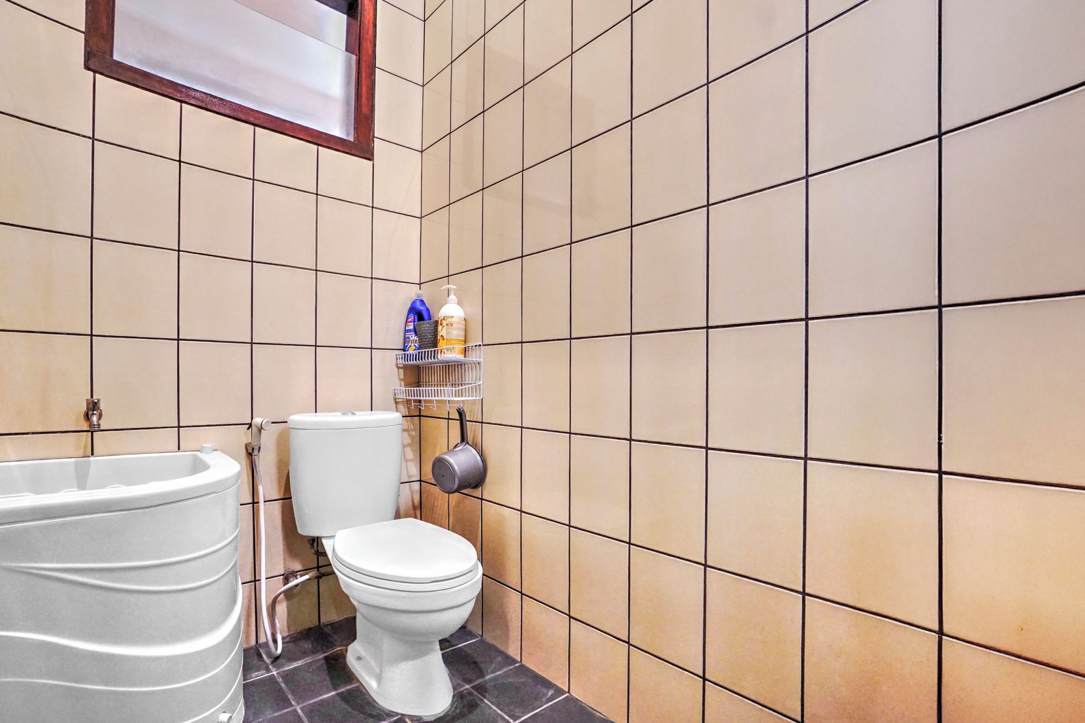 A bathroom with a bathtub, toilet, and a shelf with toiletries.