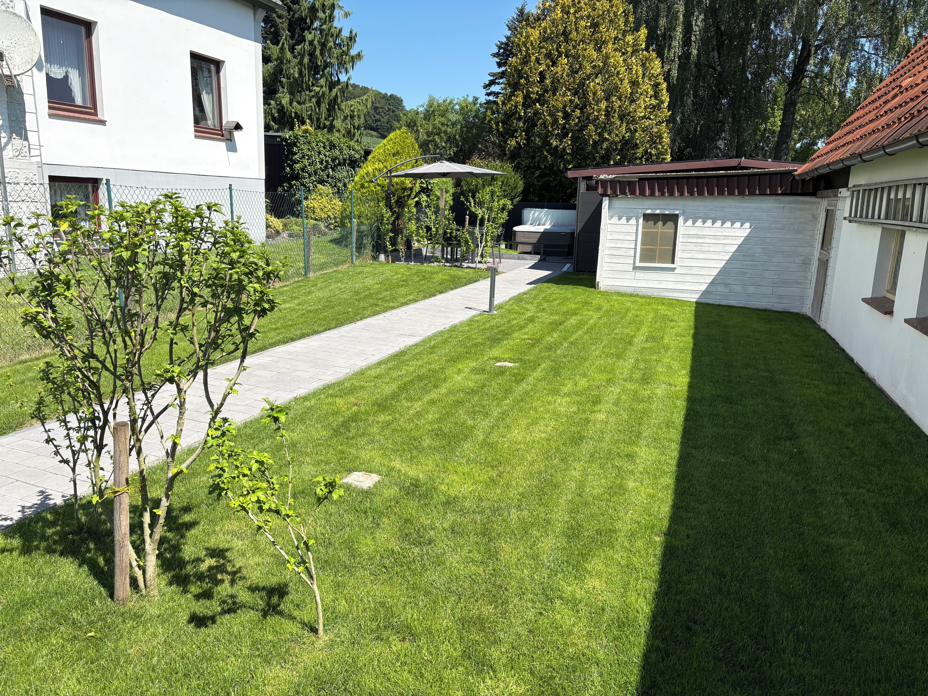 A well-maintained lawn, a pathway, and a small building with a red roof.