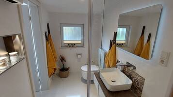 A bathroom with a white sink, mirror, and a window.
