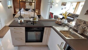 A modern kitchen with a built-in oven, a sink, and a dining area with a sofa and decorative plants. - Extertal garden chalet with heated outdoor whirlpool Dogs free of charge (Extertal)