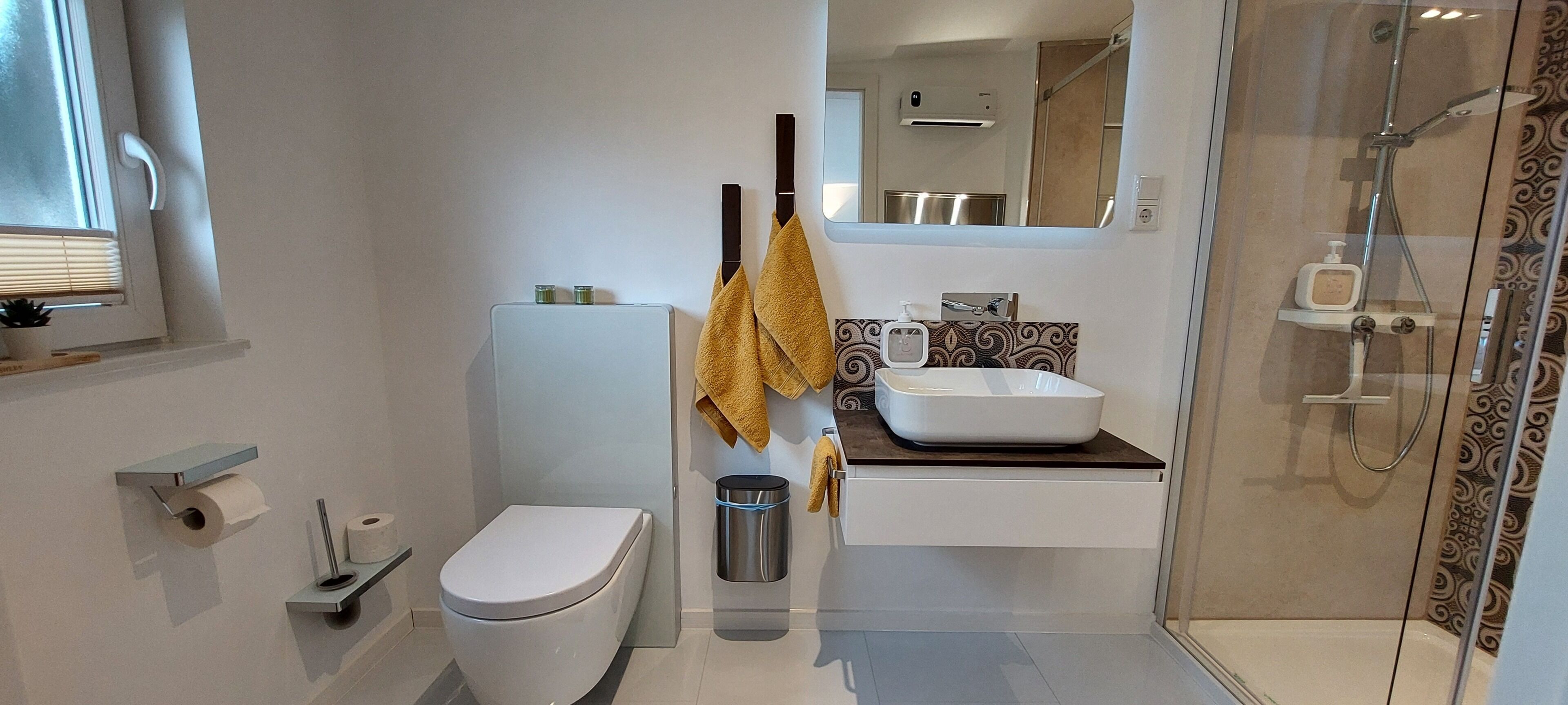 A modern bathroom with a toilet, sink, and shower.