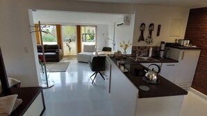A modern kitchen with a central island, a dining area with a sofa, and a view through a glass door to an outdoor patio. - Extertal garden chalet with heated outdoor whirlpool Dogs free of charge (Extertal)