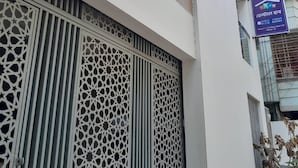 Een gebouw met een sierlijk metalen hekwerk, een bord met tekst en een meerlaags gebouw met balkons.