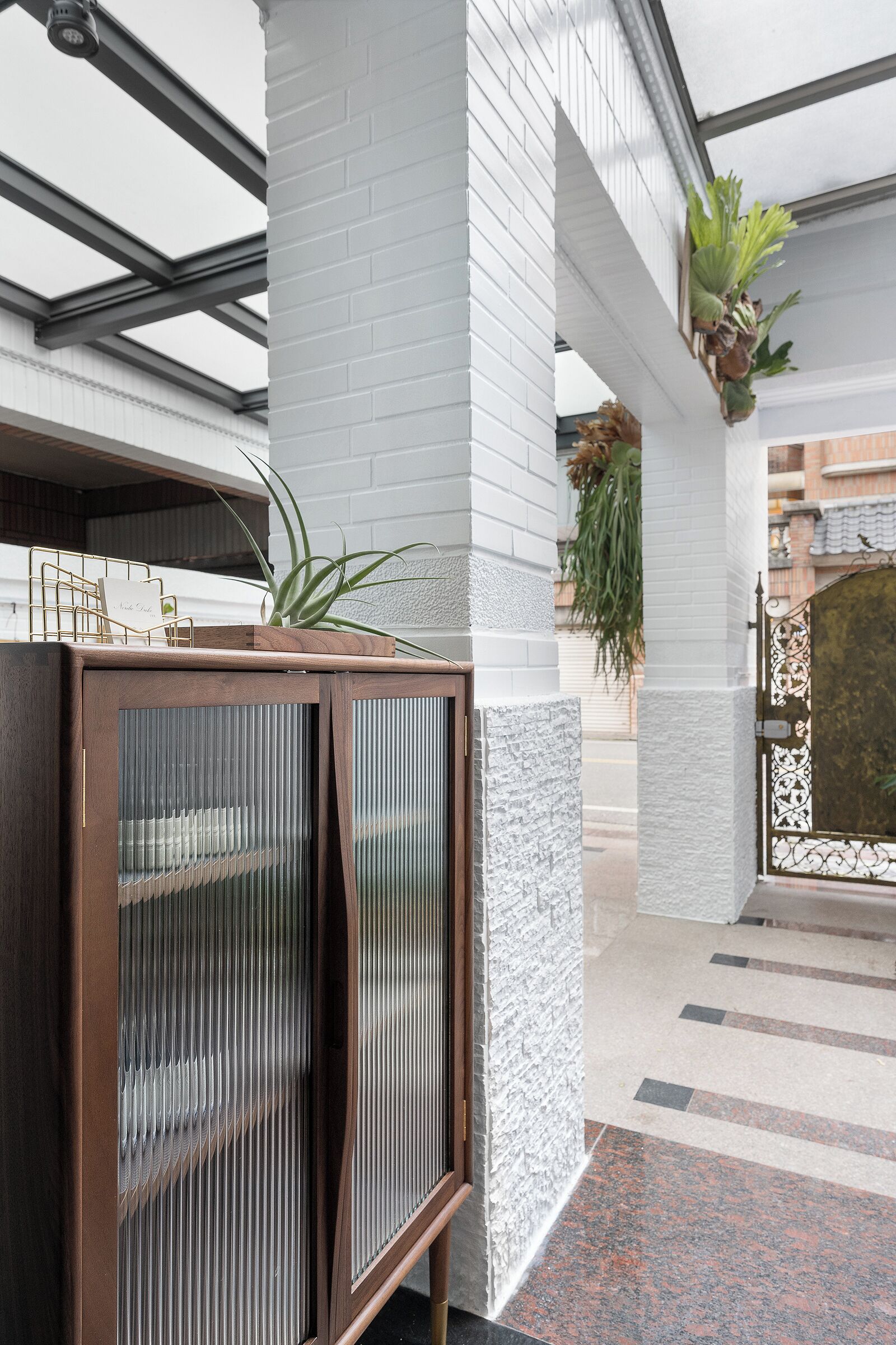 A modern interior with a wooden cabinet, white brick walls, and a metal gate.