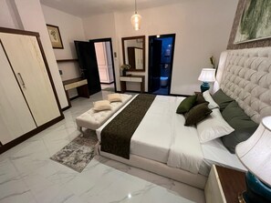 A bedroom with a bed, bedside table, lamp, and a view of the bathroom. - Luxury ocean-view apartment in Colombo 03 (Colombo)
