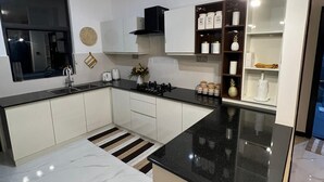 A modern kitchen with white cabinets, a black countertop, and a built-in oven.