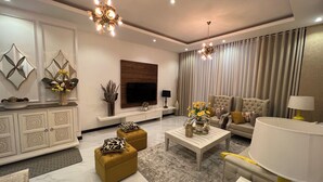 A modern living room with a TV, sofa, ottoman, coffee table, and decorative items.