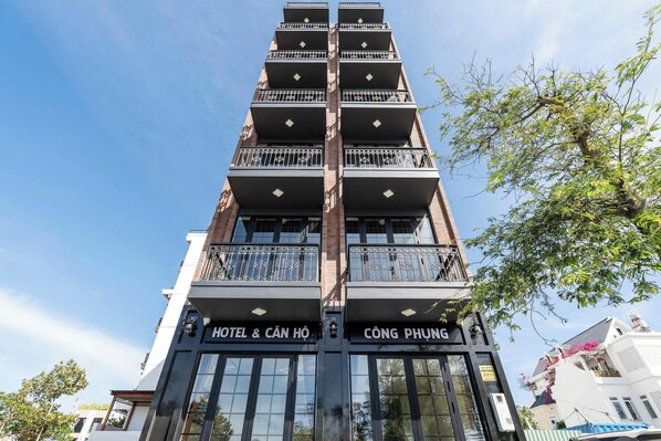 Ein mehrstöckiges Gebäude mit Balkonen, einer Beschilderung mit 'HOTEL & CÁNH HỒI' und 'CÔNG PHƯNG'.