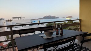 Un balcon avec une table, deux bouteilles et un saladier.