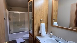 Ein Badezimmer mit Duschkabine, Toilette, Waschbecken und Spiegel.