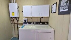 Ein Waschraum mit Waschmaschine, Trockner, Warmwasserbereiter und Schrank.