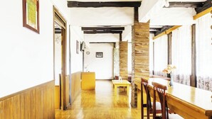 A long dining hall with wooden floors, a central table, and chairs. - Cottage Syariah GS Rumah Kayu (Parongpong)