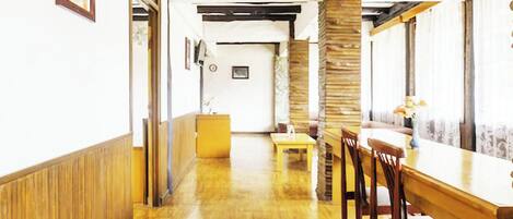 Un comedor amplio con suelo de madera, una mesa central y sillas.