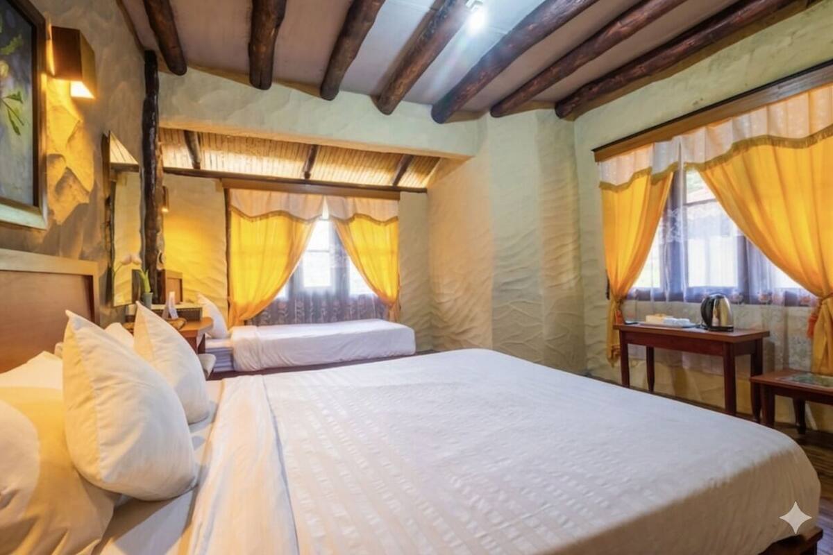 A hotel room with a large bed, a bedside table, a lamp, and a window with curtains.