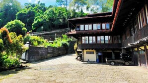 A traditional building with a tiled roof, a paved courtyard, and a truck parked outside. - Cottage Syariah GS Rumah Kayu (Parongpong)