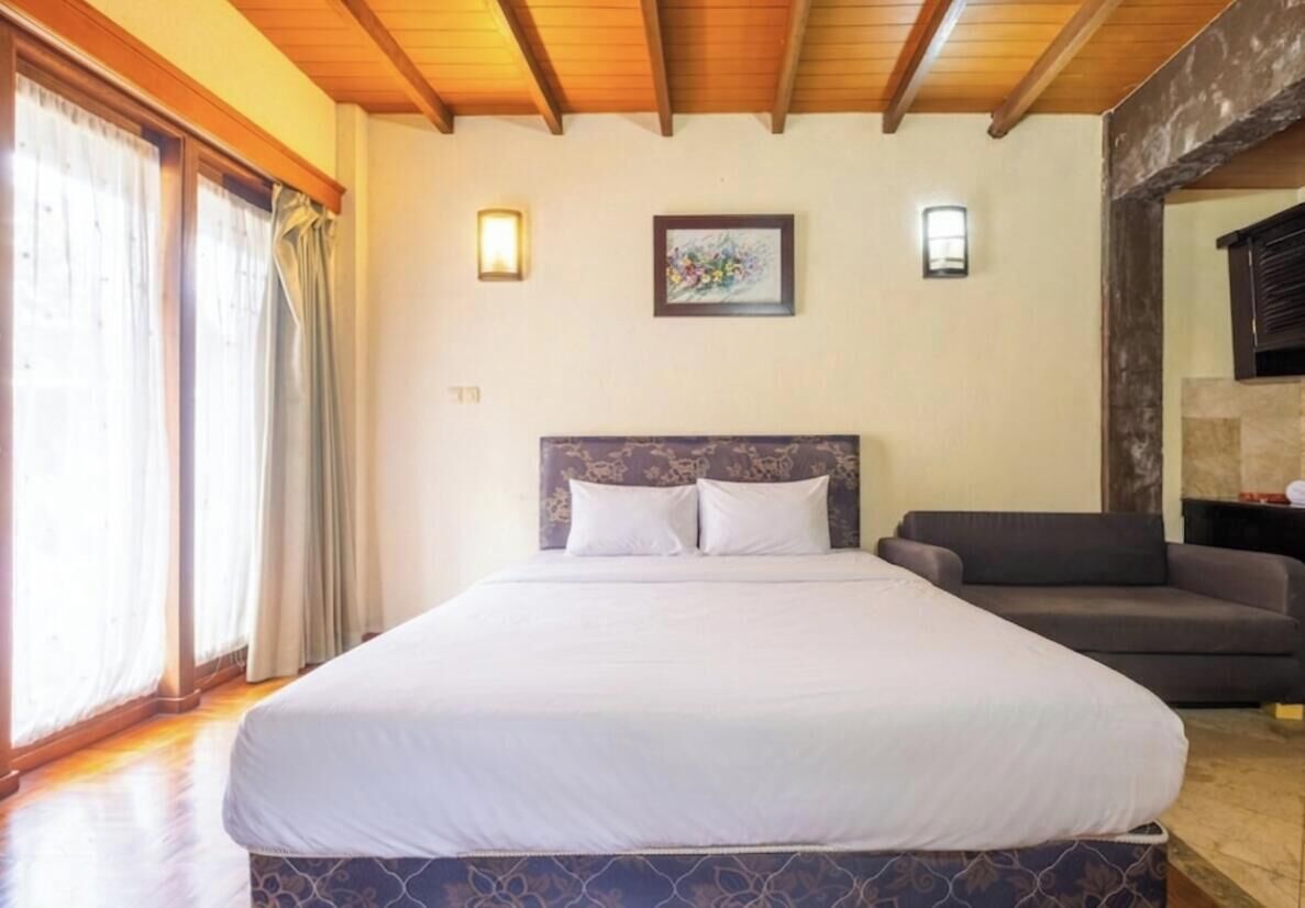 Un dormitorio con cama, sofá y un cuadro en la pared.