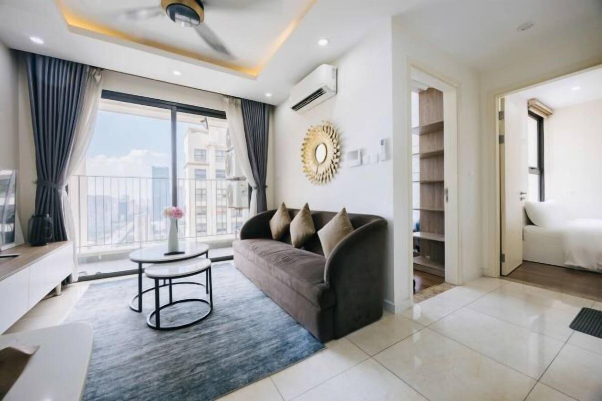 A modern living room with a sofa, a coffee table, and a view of the city through large windows.