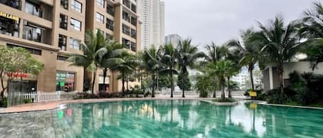 A swimming pool surrounded by palm trees and tall buildings.