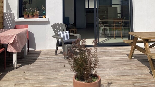 A modern building with a patio area, a table with a tablecloth, a chair, and a potted plant.