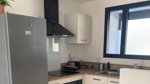 A modern kitchen with a built-in oven, a refrigerator, and a window above the sink.