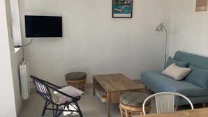 A living room with a TV, a sofa, a table, and two chairs.