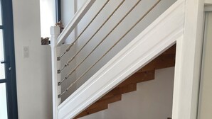 A staircase with white railings and wooden steps, leading to an upper floor. There are wicker baskets at the bottom of the stairs.