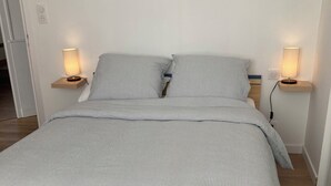 A bed with striped bedding, two bedside lamps, and a wooden headboard.