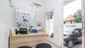 Un espace d’accueil avec un comptoir en bois, une grande œuvre d’art abstraite, une horloge et une porte donnant sur l’extérieur.