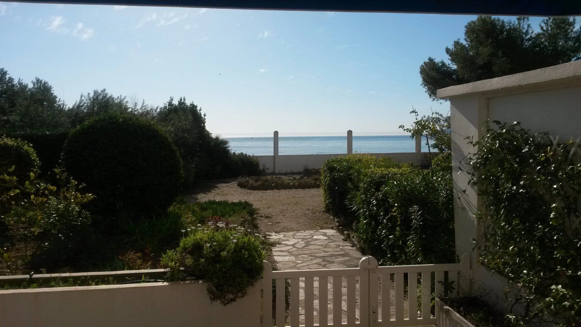 A pathway leading to a beach with a fence and greenery.