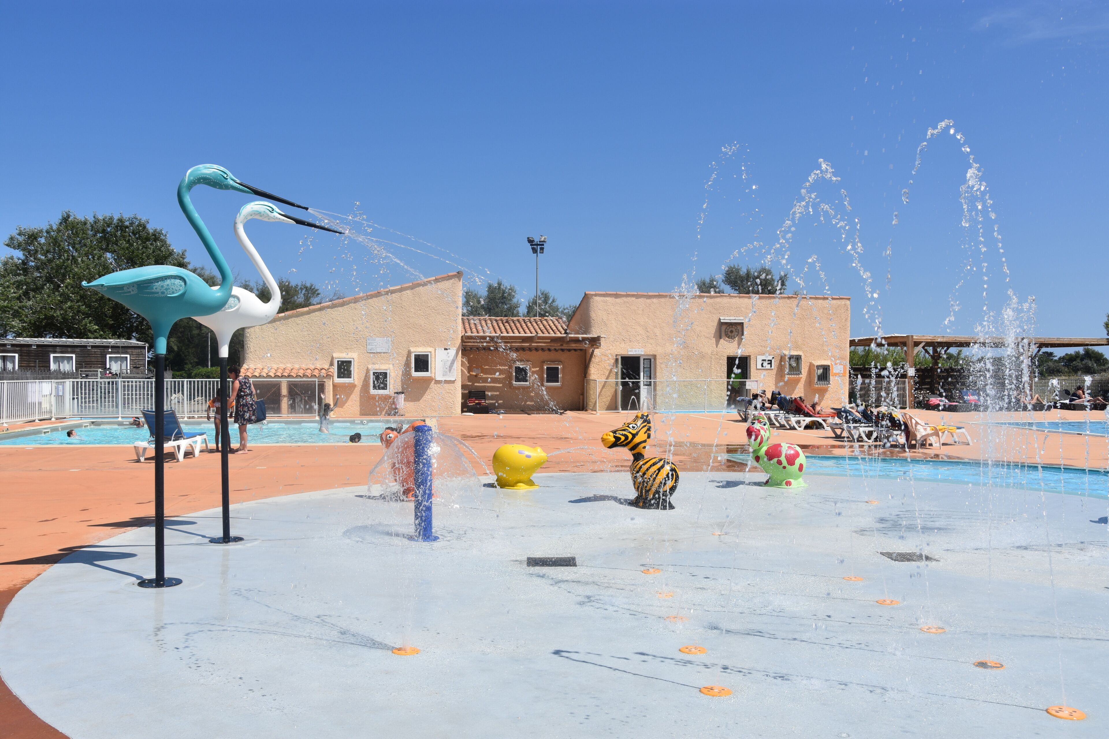Um espelho d'água com esculturas de animais, uma piscina e um edifício com telhado em azulejos.